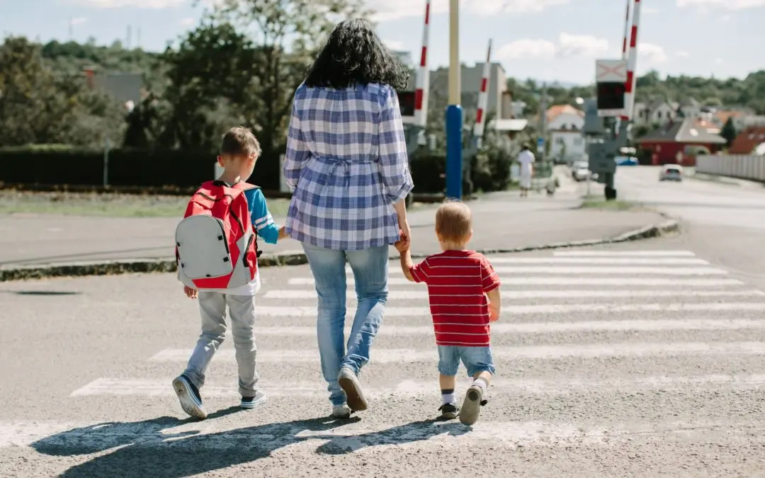 Woman and two children crossing street together.