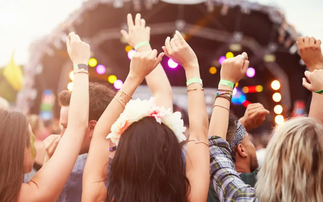 People dancing with raised hands at concert.