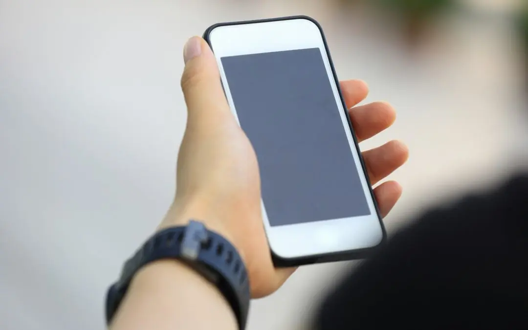 Hand holding smartphone with blank screen.