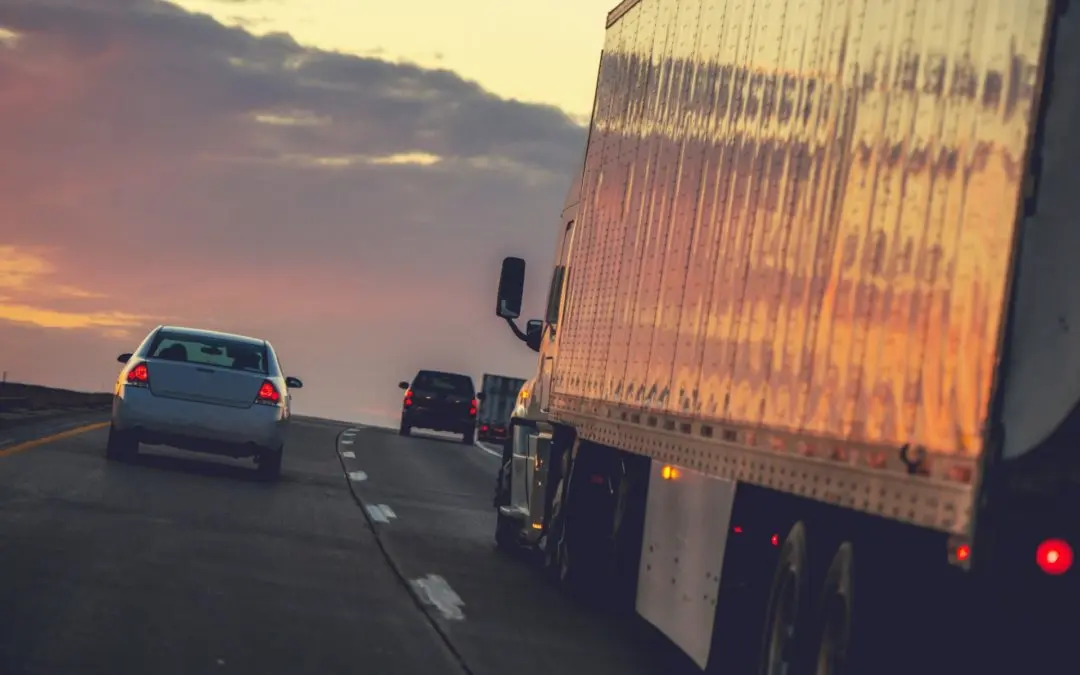 Cars and semi truck driving at sunset.