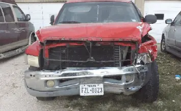 Red truck with severe front-end damage.