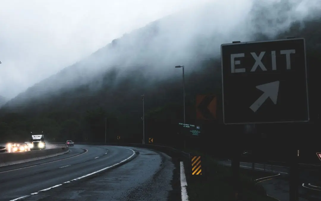 Road with exit sign and foggy atmosphere.