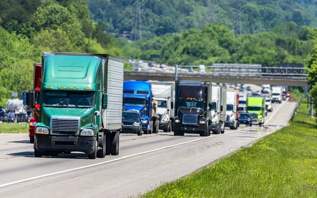 Trucks driving down a highway with traffic.