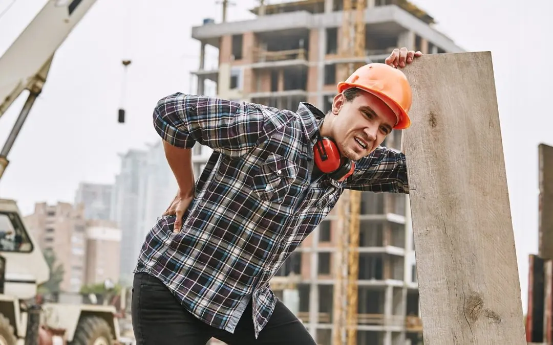 Construction worker holding back with visible pain.