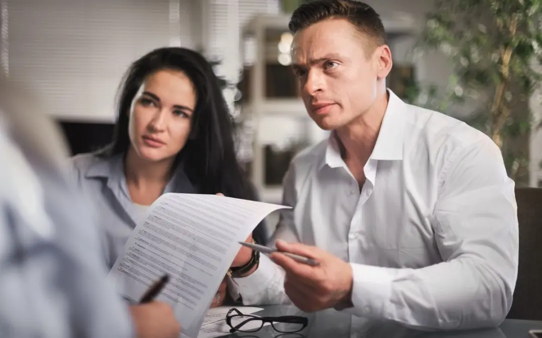 Couple discussing legal paperwork with lawyer.