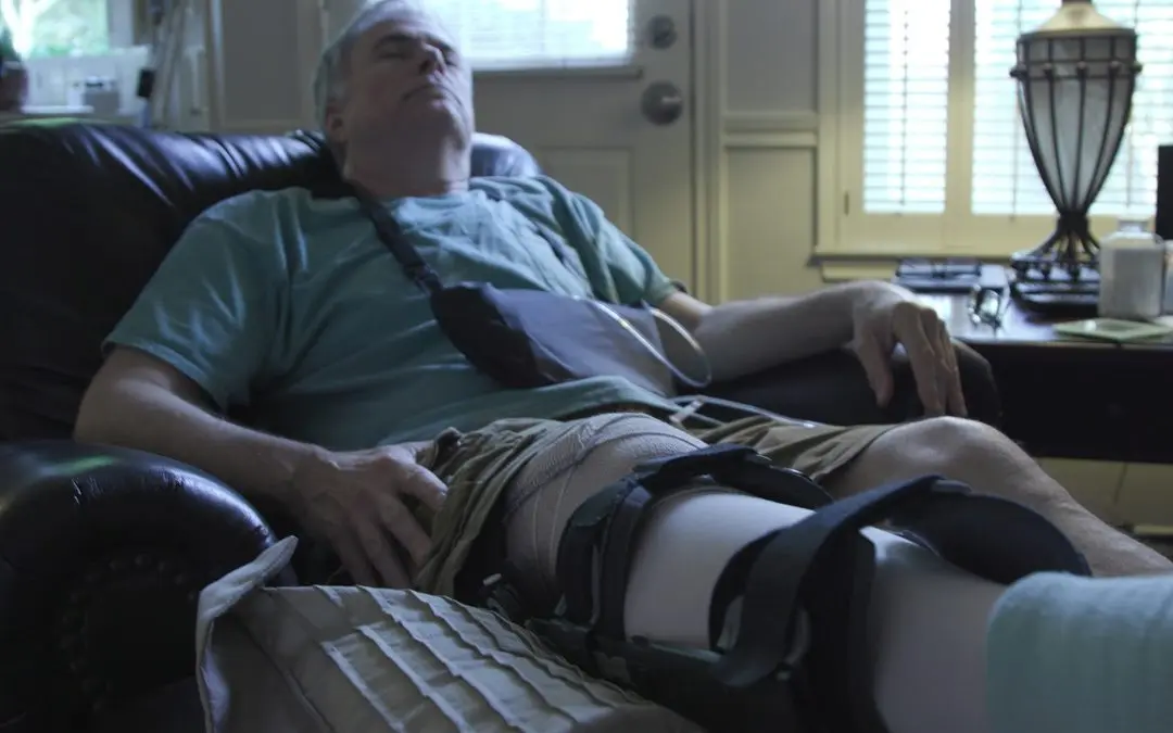 Man resting with a leg brace and sling.