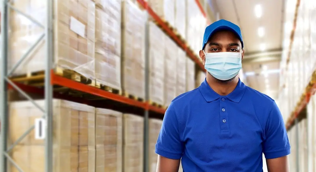 Warehouse worker wearing mask and blue uniform.