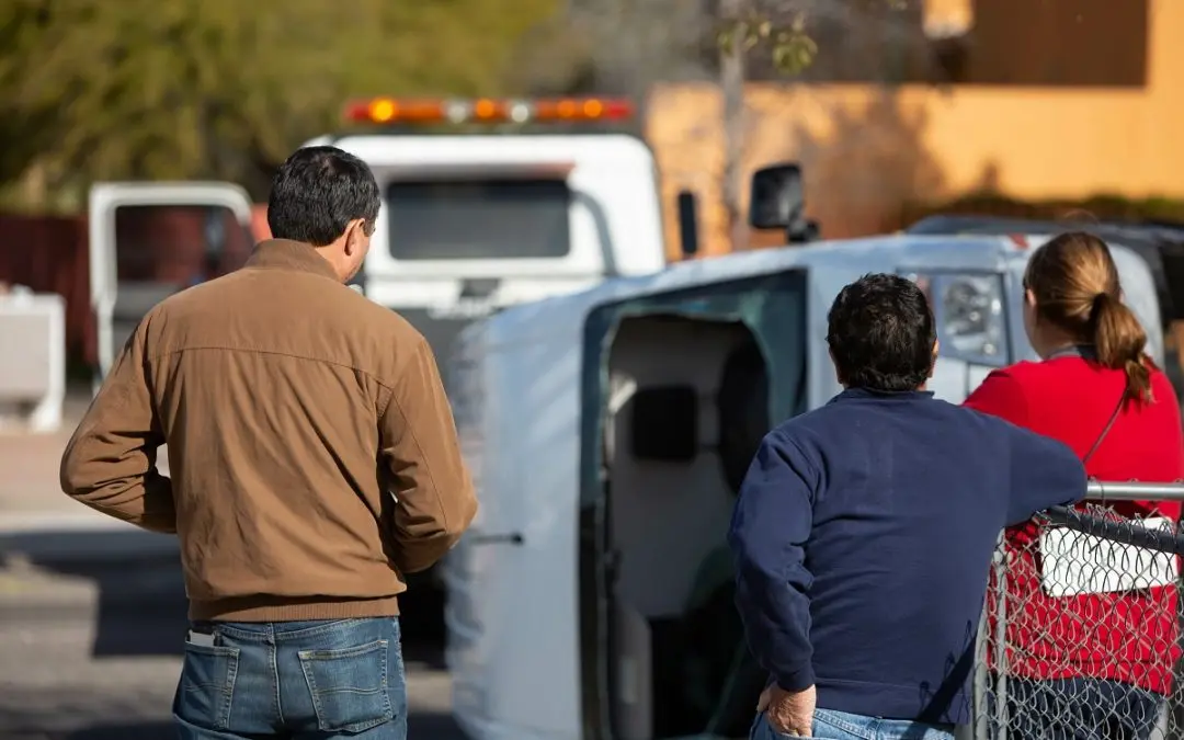 People observing overturned vehicle at accident scene.