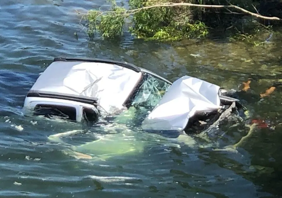 Car submerged in water with significant damage.