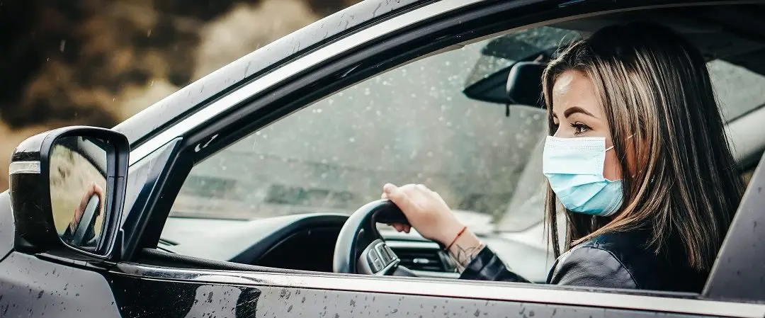 Woman wearing a mask while driving a car.