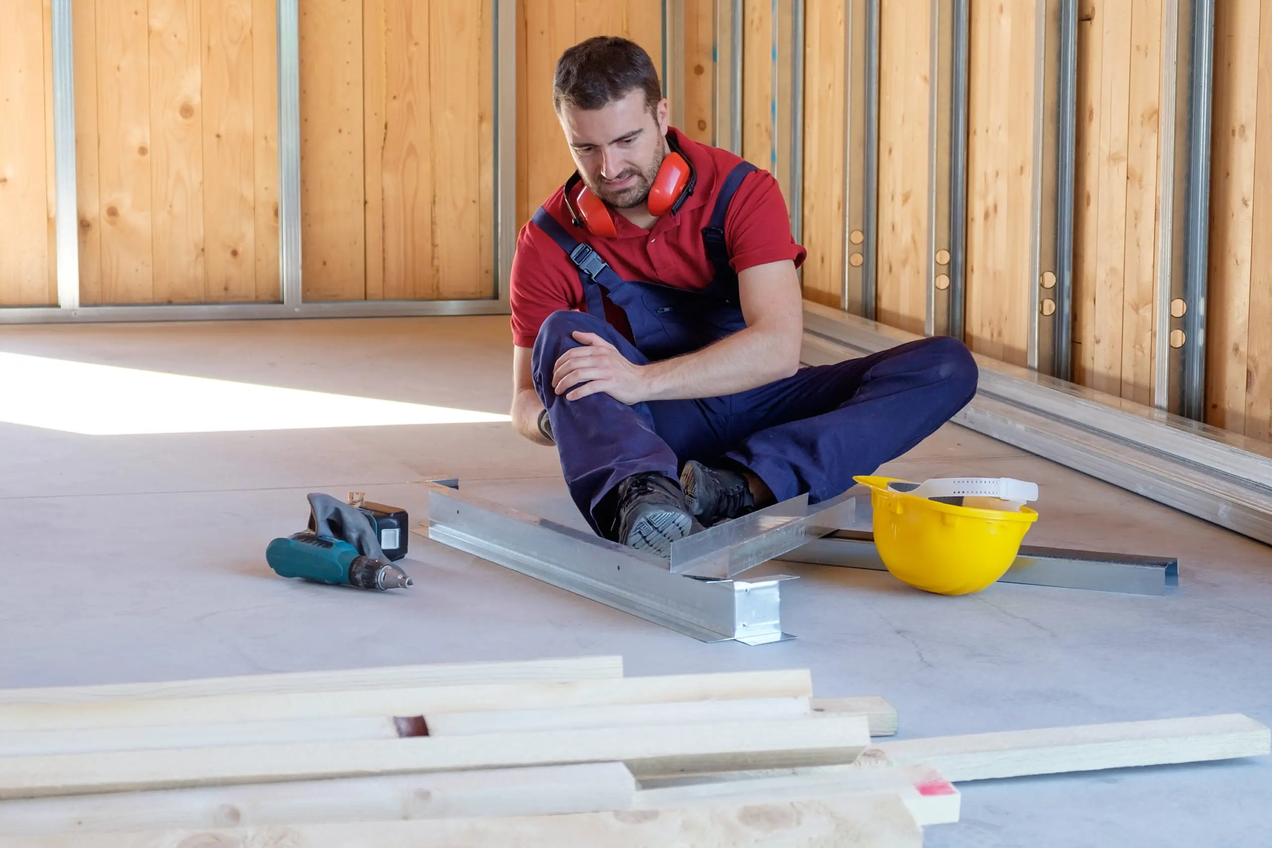 Construction worker sitting with leg injury on site.