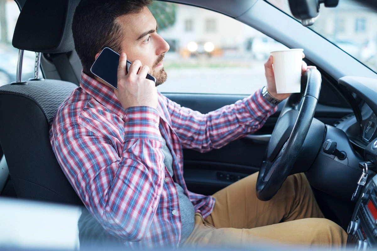 Man talking on phone while holding coffee cup.