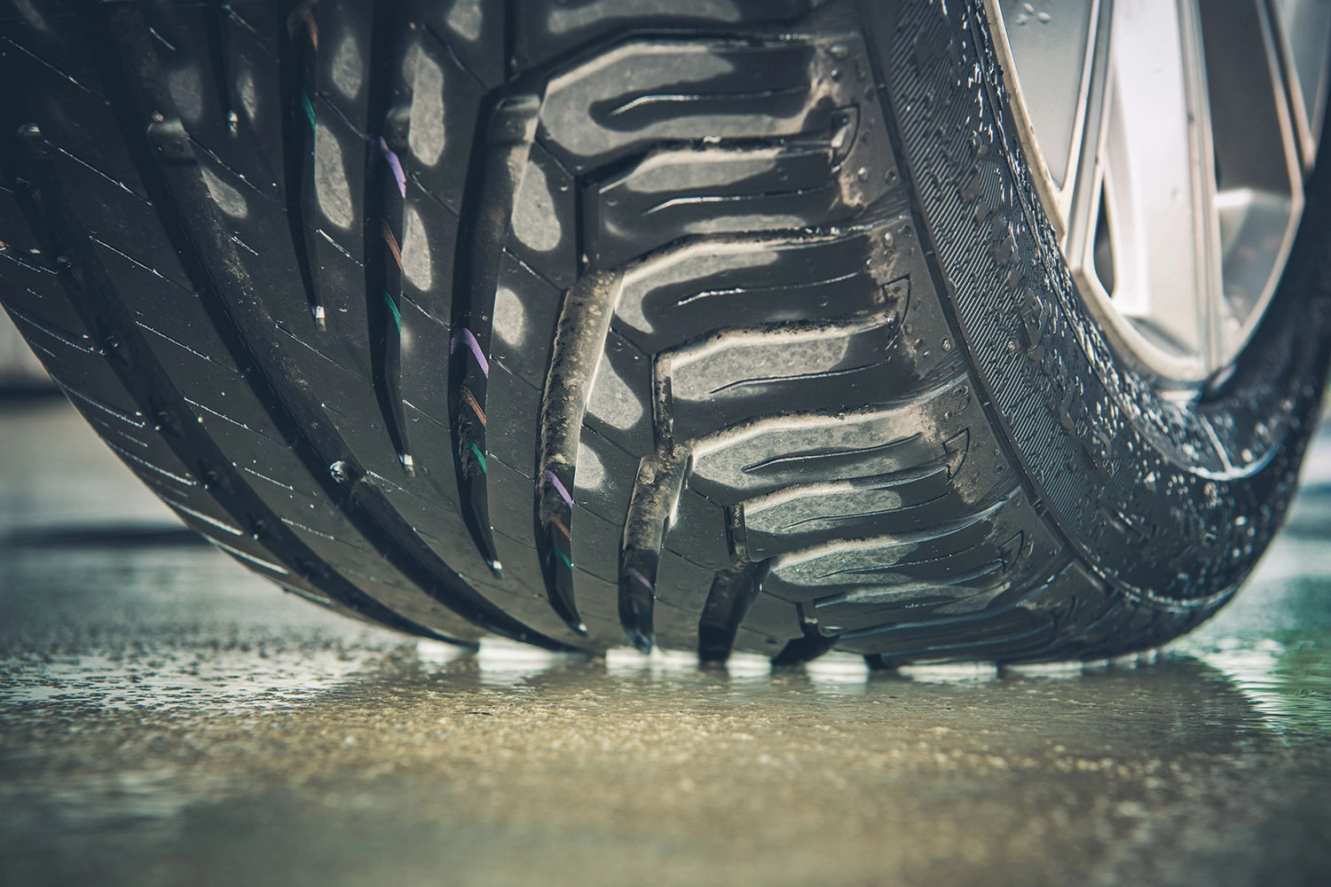Close-up of wet car tire on pavement.