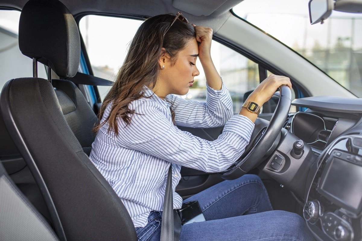 Fatigued woman resting in parked car.