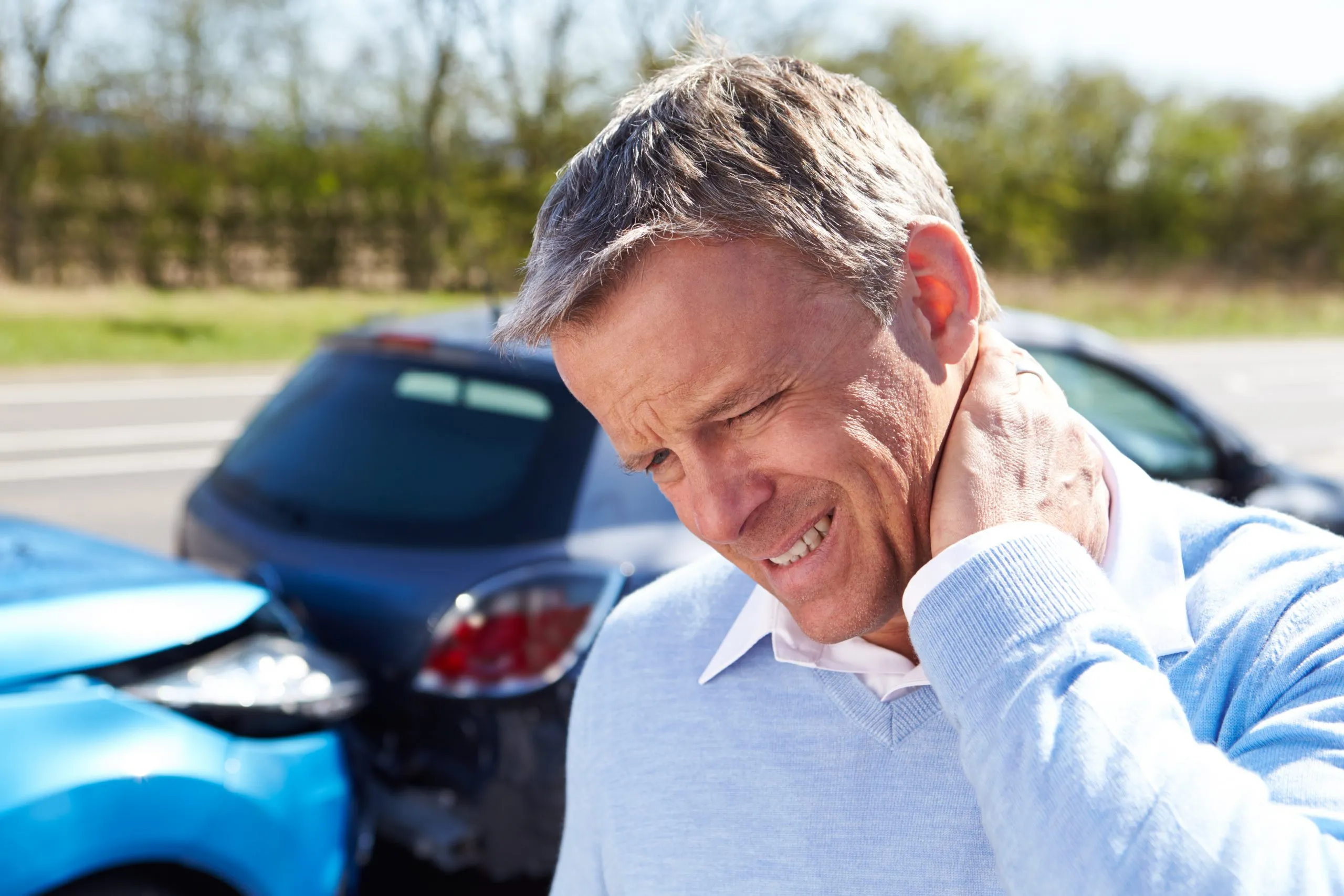 Injured man holding neck after car accident.