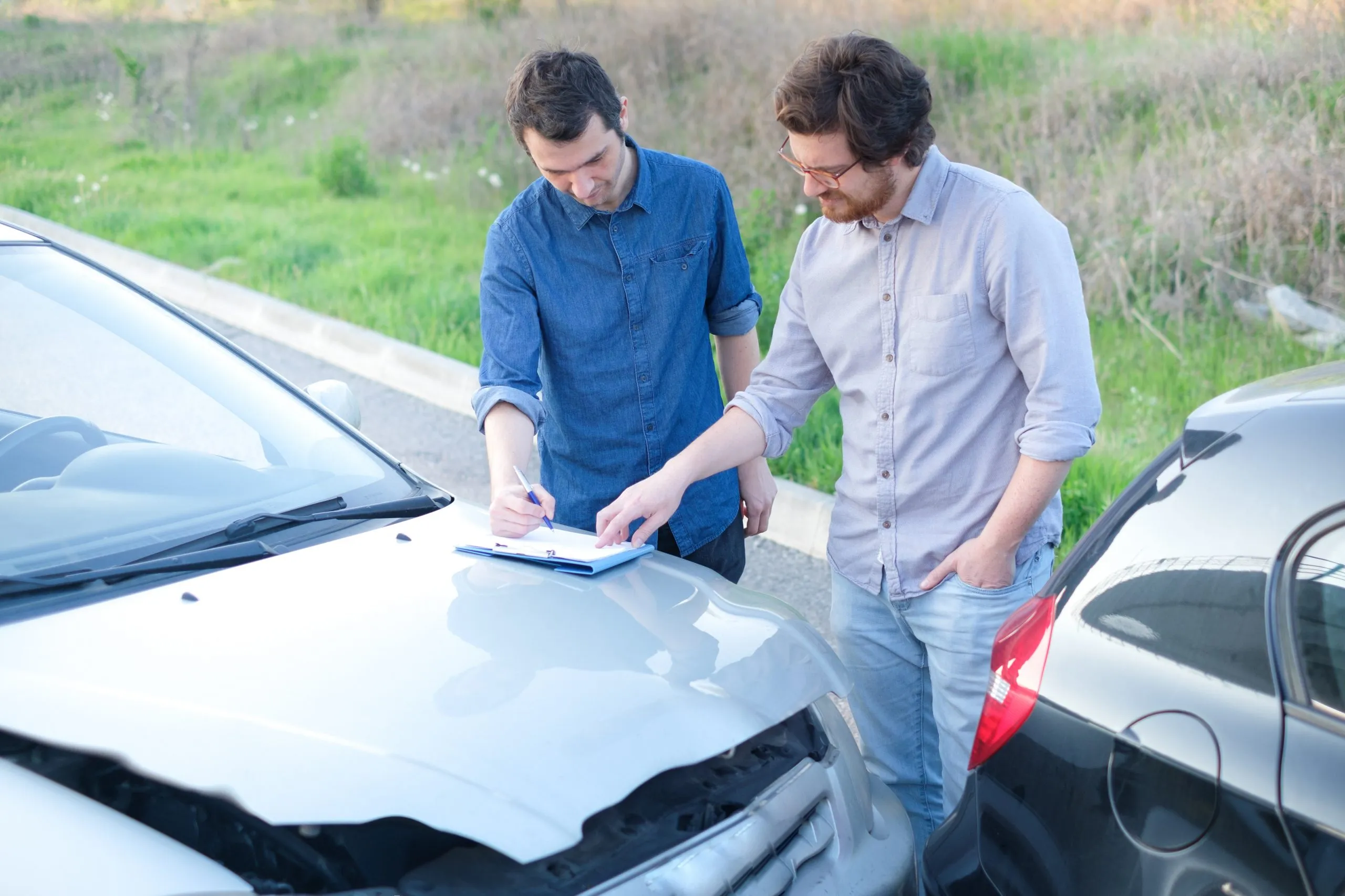 Two men document minor car accident damage.