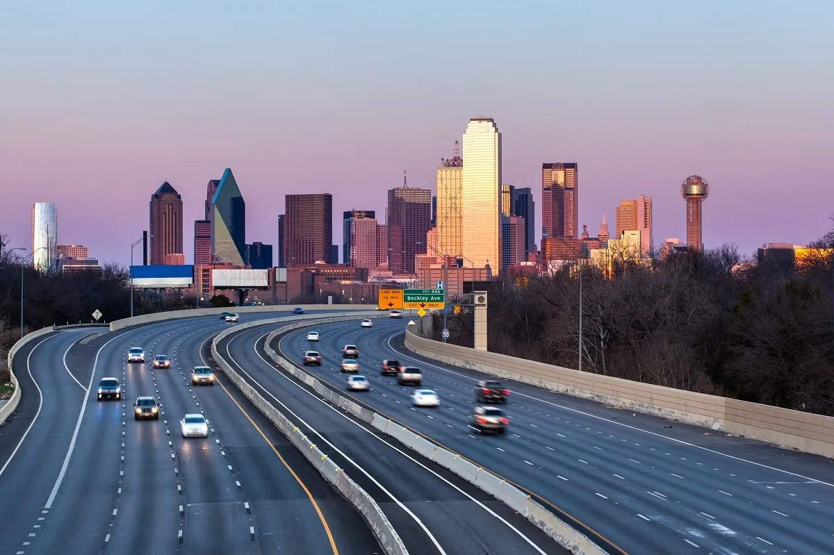 Cars driving toward downtown Dallas at sunset.