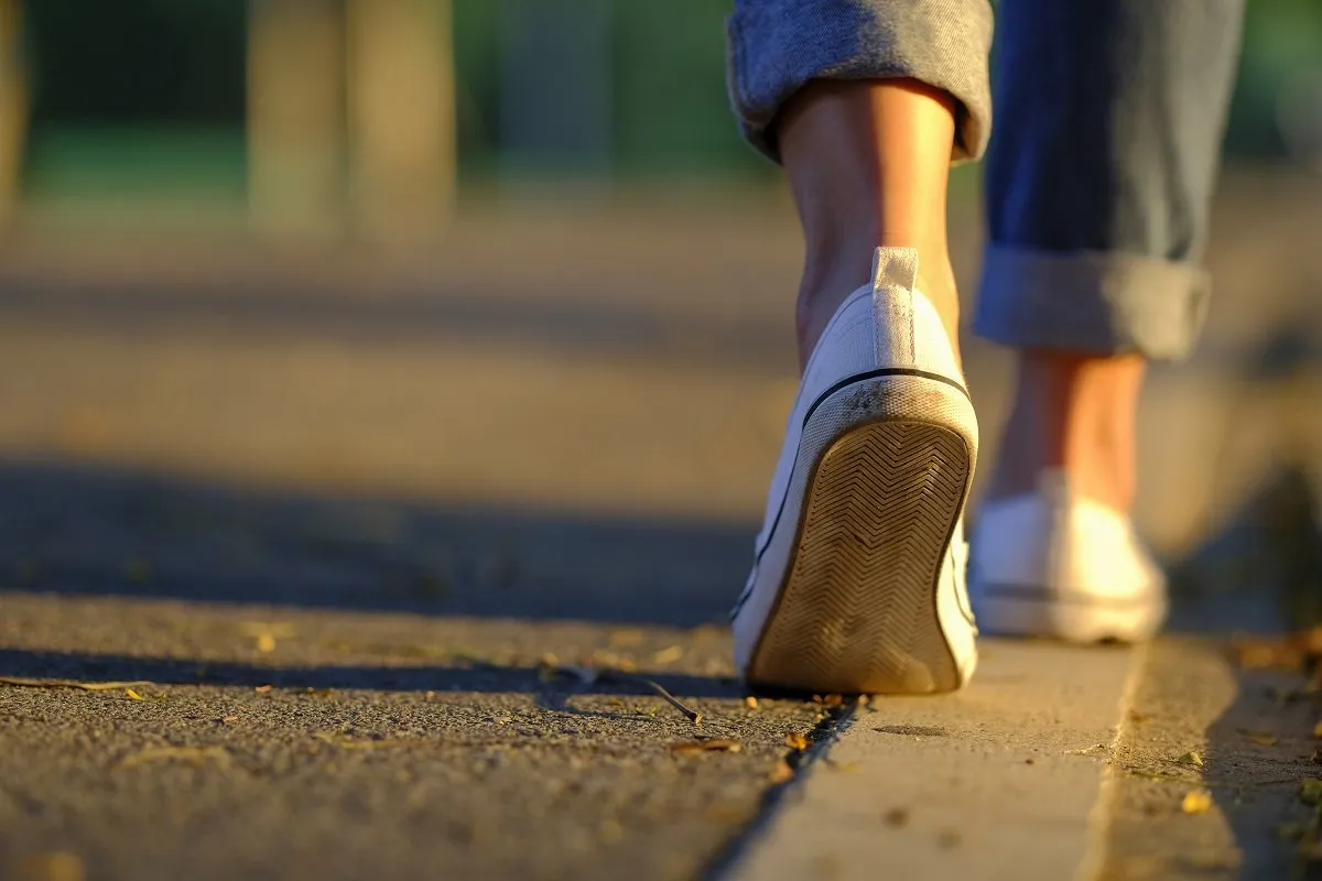 Close-up of person walking on sidewalk.