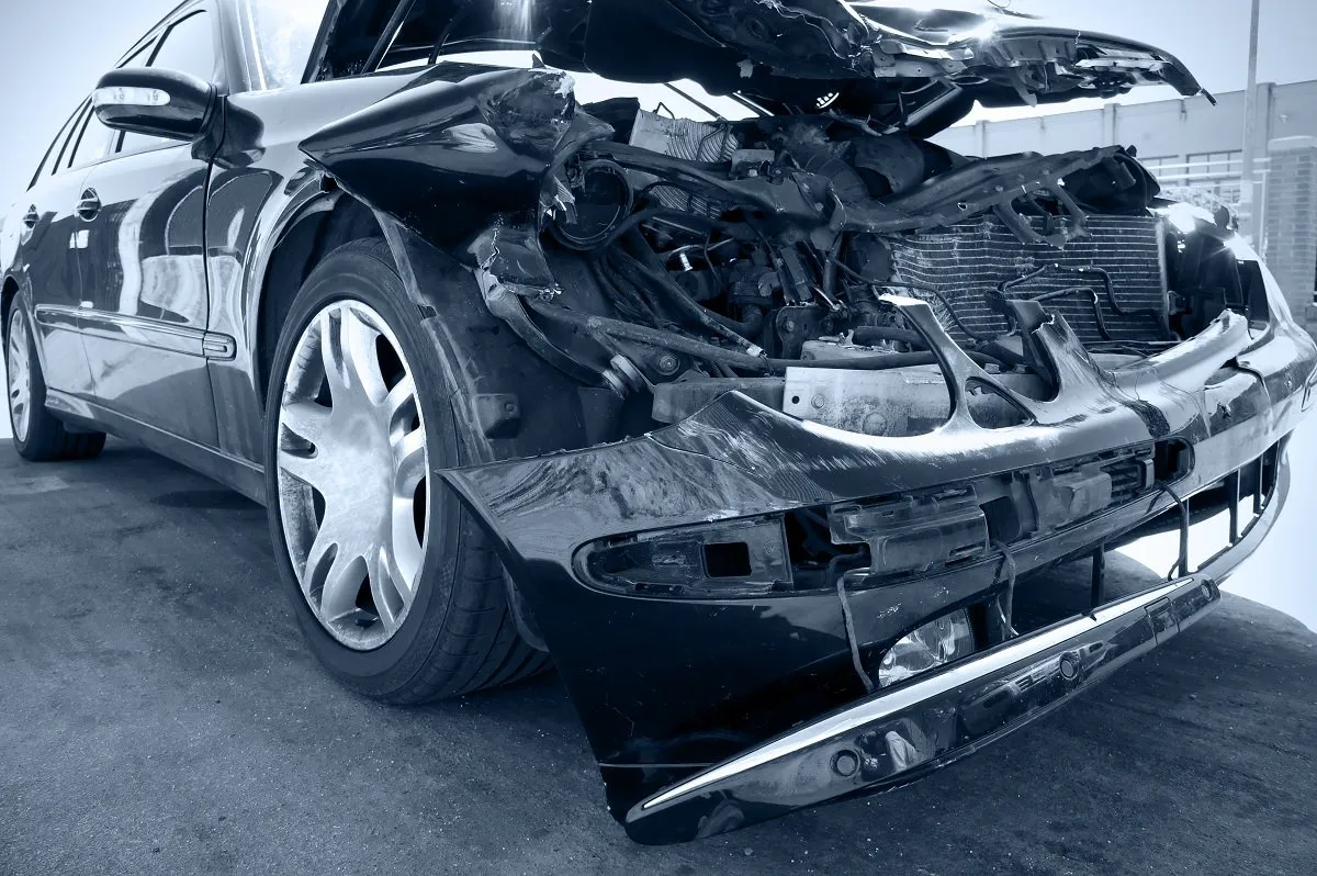 Car with significant front-end damage and debris.