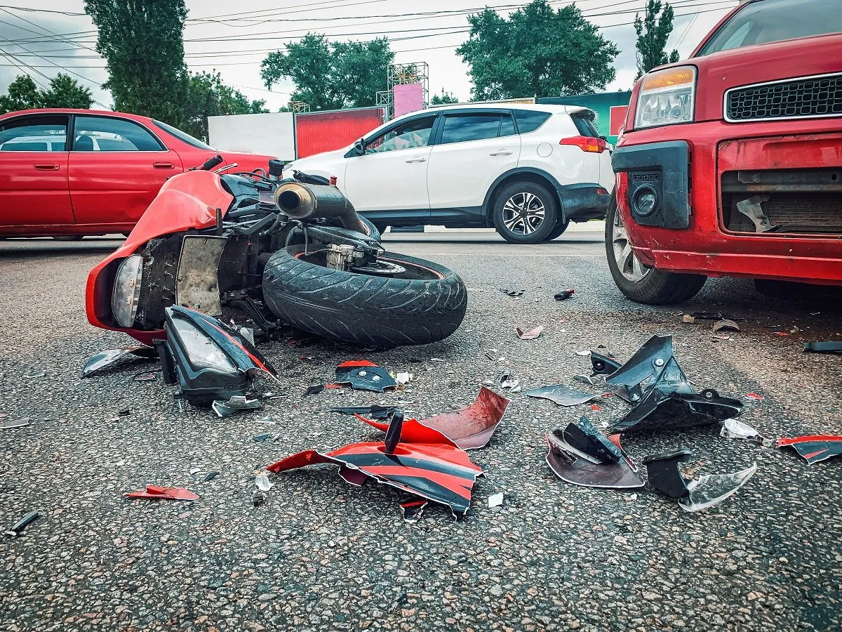 Damaged motorcycle and car debris after crash.