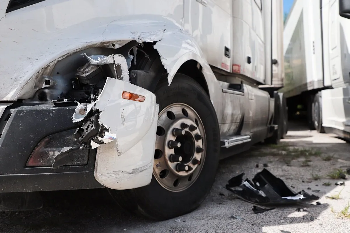 Damaged semi-truck with broken front fender.