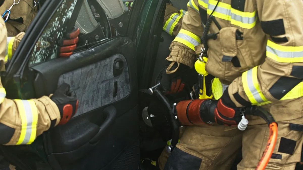 Firefighters using hydraulic tools in car rescue.