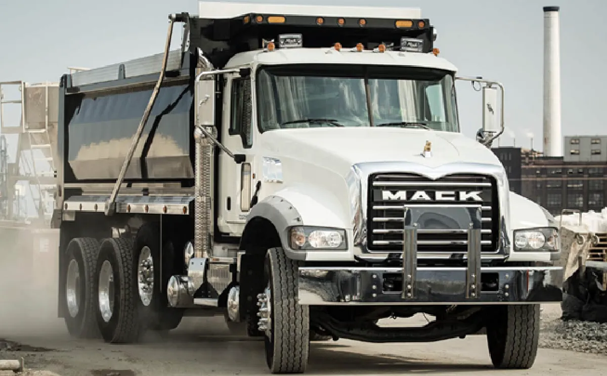 White Mack dump truck driving on construction site.