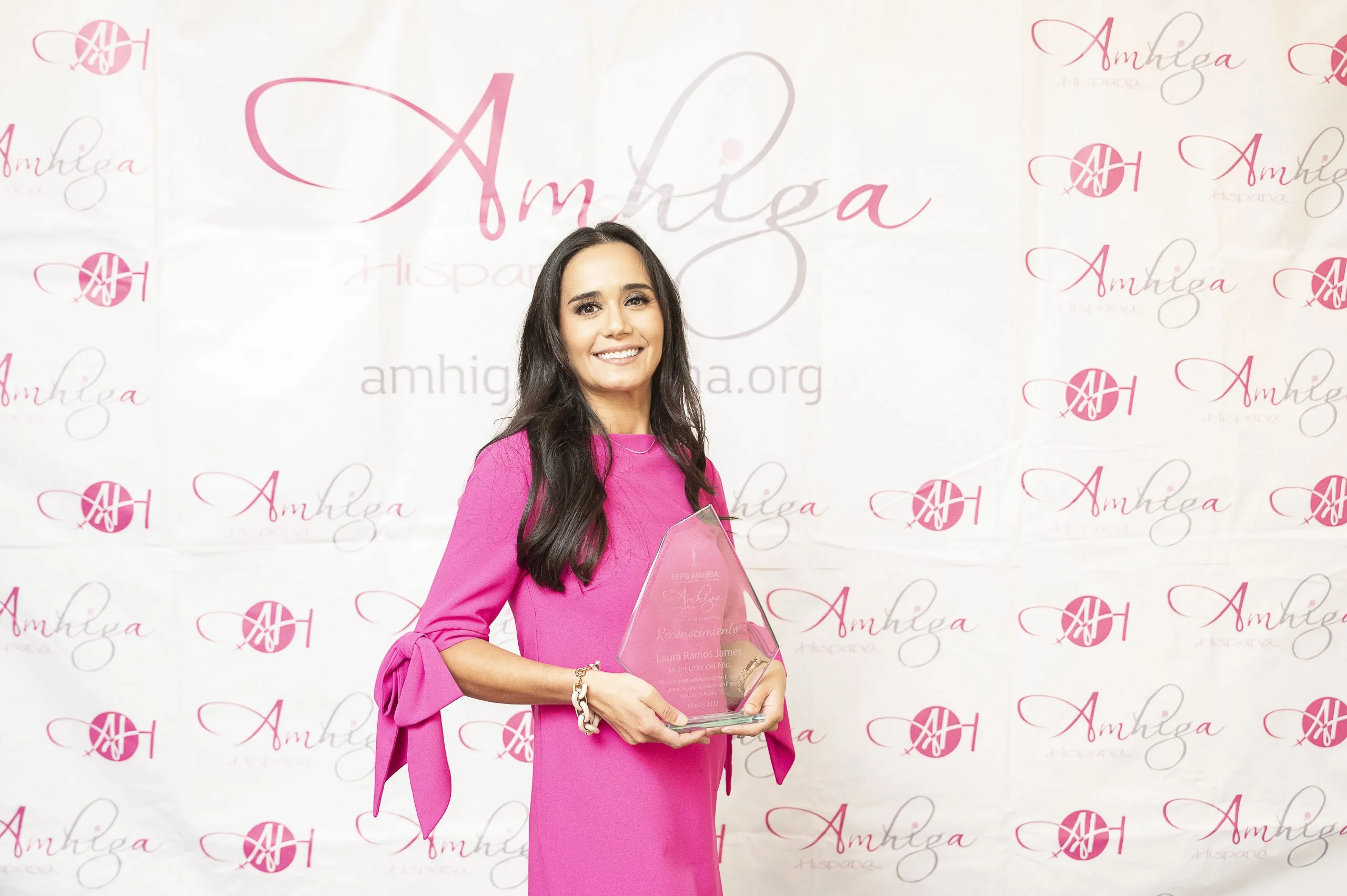 Woman in pink dress holding achievement award.