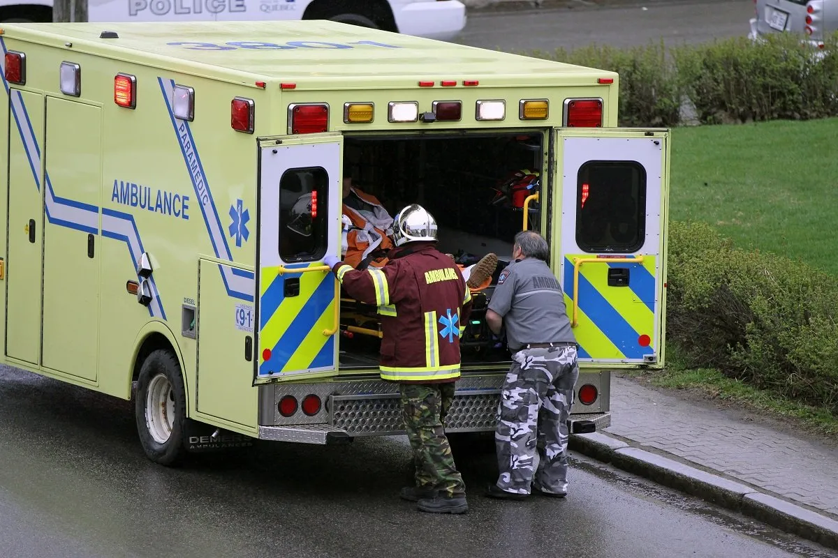 Paramedics loading patient into ambulance vehicle.