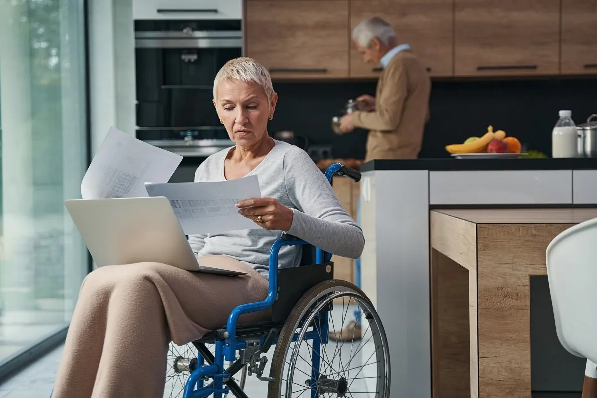 Woman in wheelchair reviewing documents at home.