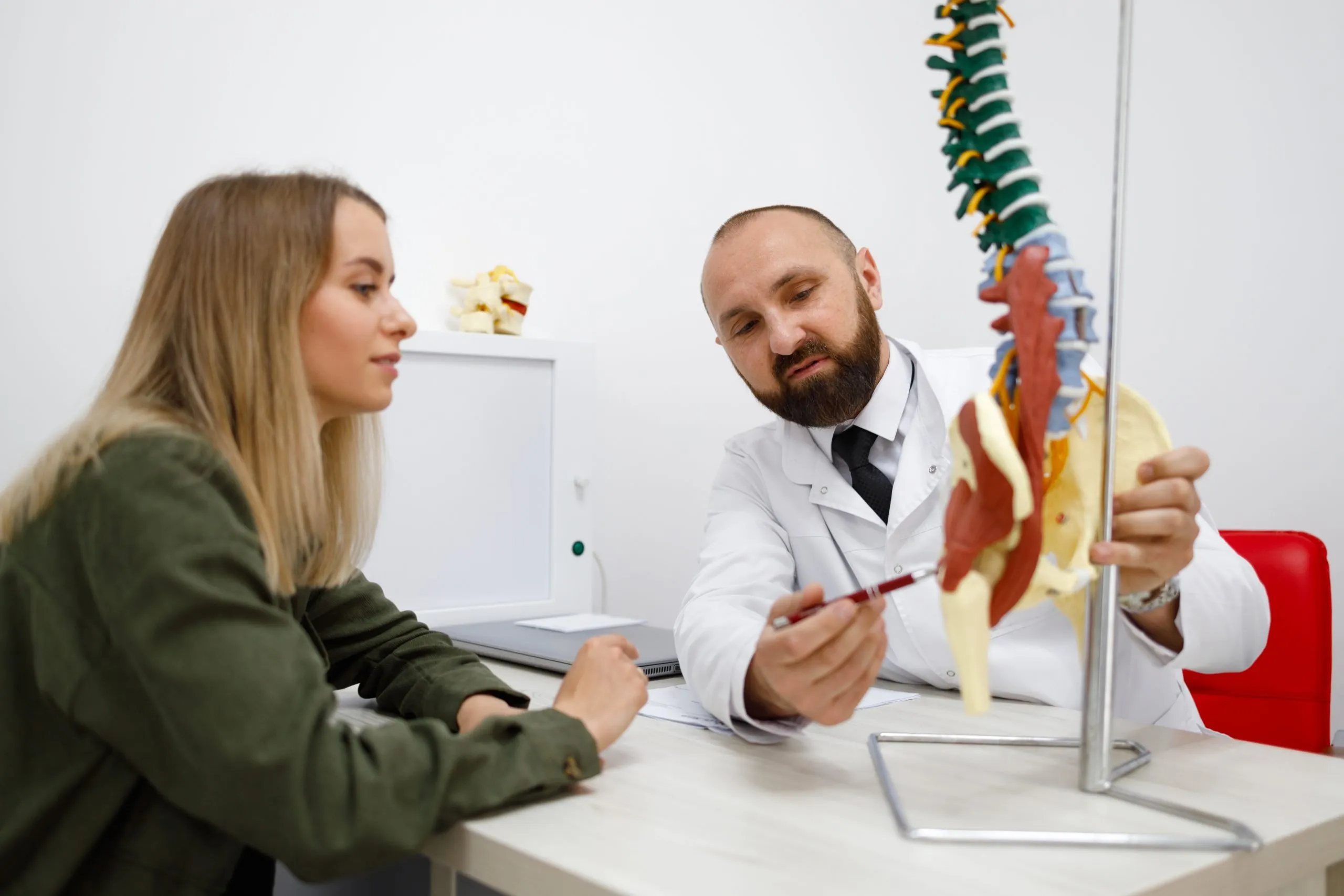 Doctor showing spine model to female patient.