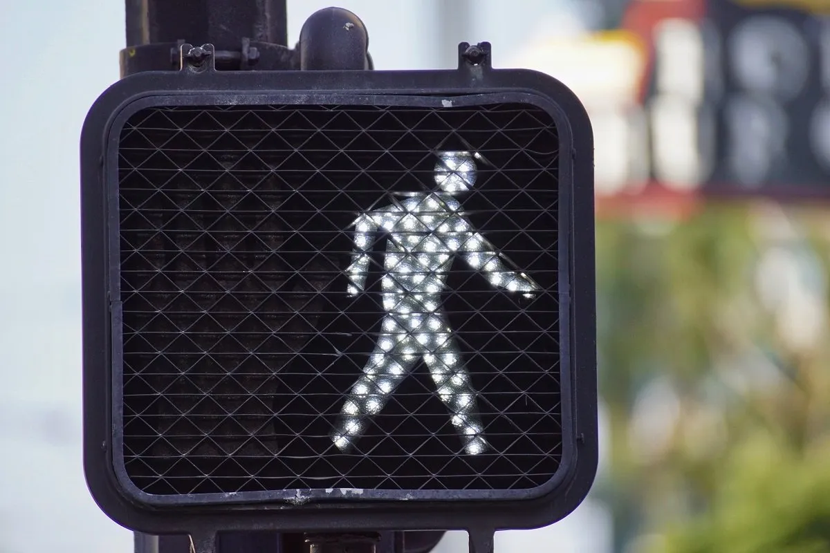 Pedestrian signal with accident headline in Spanish.