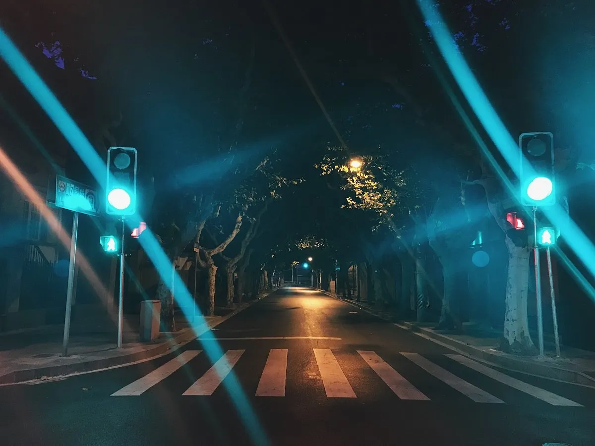 Empty crosswalk under green traffic lights, at night.