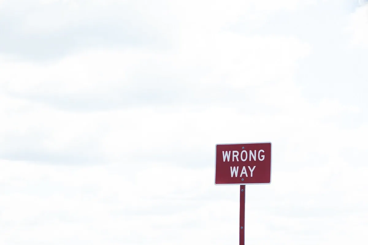 Red "Wrong Way" road sign, cloudy background.