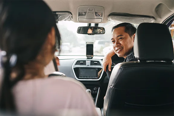 The driver is smiling and talking to the front passenger.