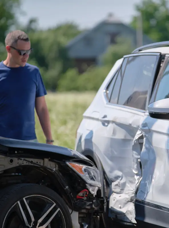 A man is inspecting damage after a car accident.
