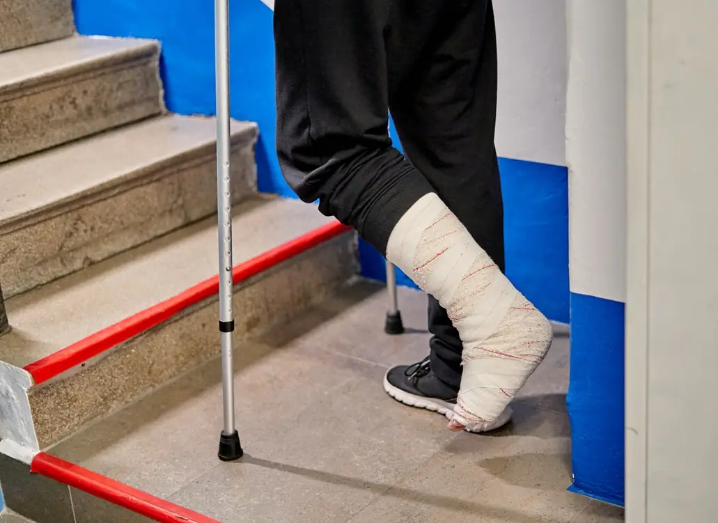 Person with leg cast using crutches upstairs.