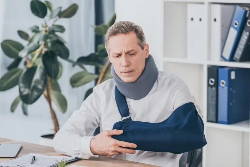 Injured man with neck brace and arm sling.