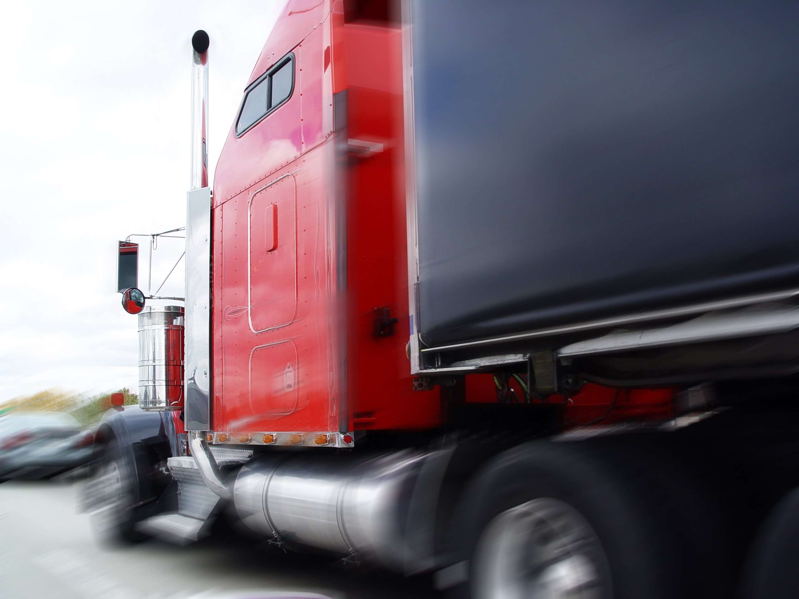 A red semi-truck and trailer in motion