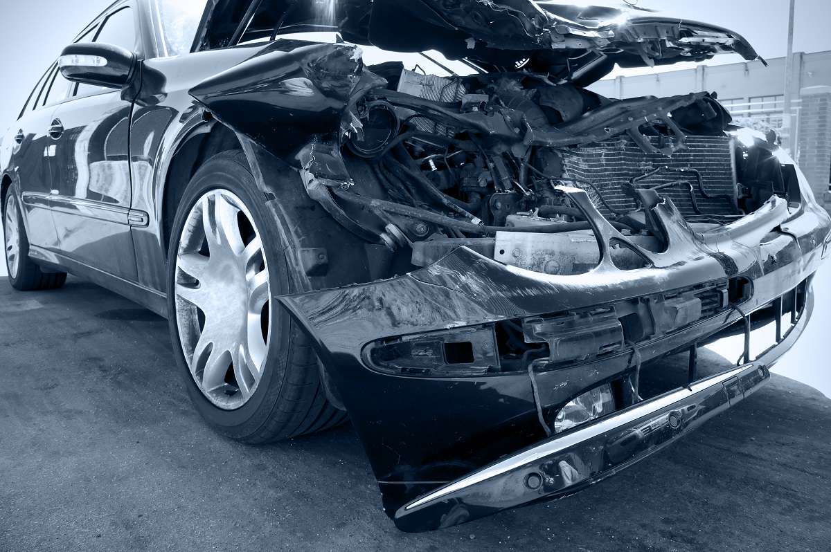 The front end of a gray car is ripped open and heavily damaged.