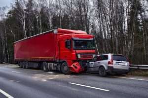 A silver SUV is crashed into the damaged front of a red truck.