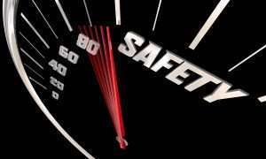 A speedometer with a red needle that is moving toward the word safety.