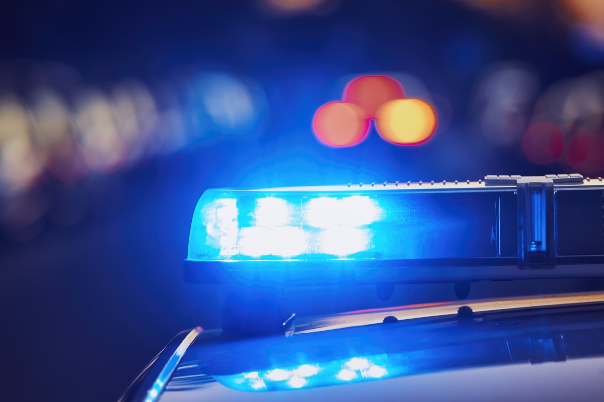A parked police car at night with the blue light lit up.