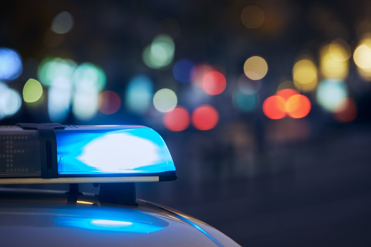 The blue flashing light on top of a police car at night.