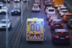An ambulance driving in traffic with lights engaged