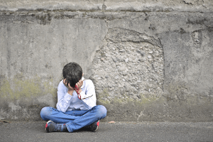 A sad boy sitting with his face in his hands