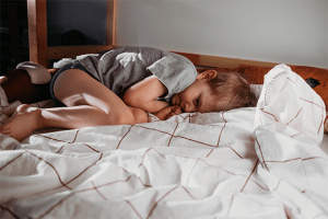 A sad little boy curled up in bed